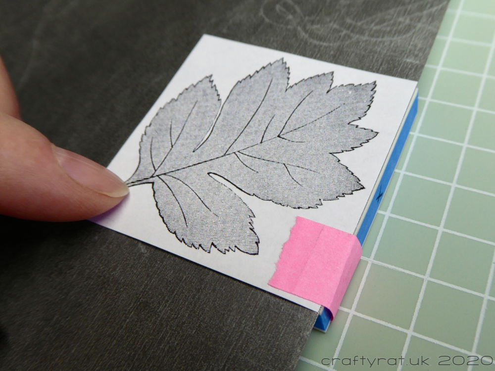 The printed leaf image is taped onto the carving block and the tracedown paper is placed between the two.