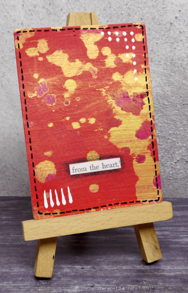 Red and gold art card on a mini easel.