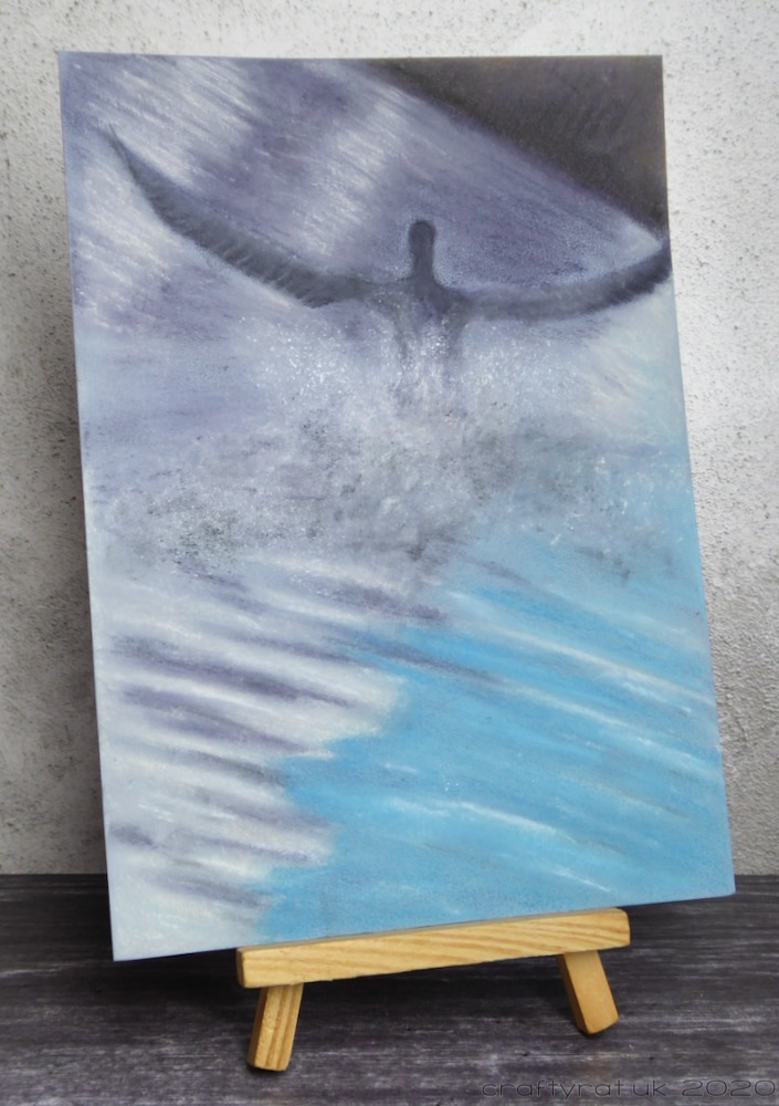 The cormorant drawing displayed on a small wooden easel.