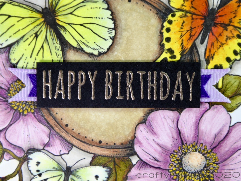 A close-up of the "Happy Birthday" sentiment with the strips of ribbon beneath it.