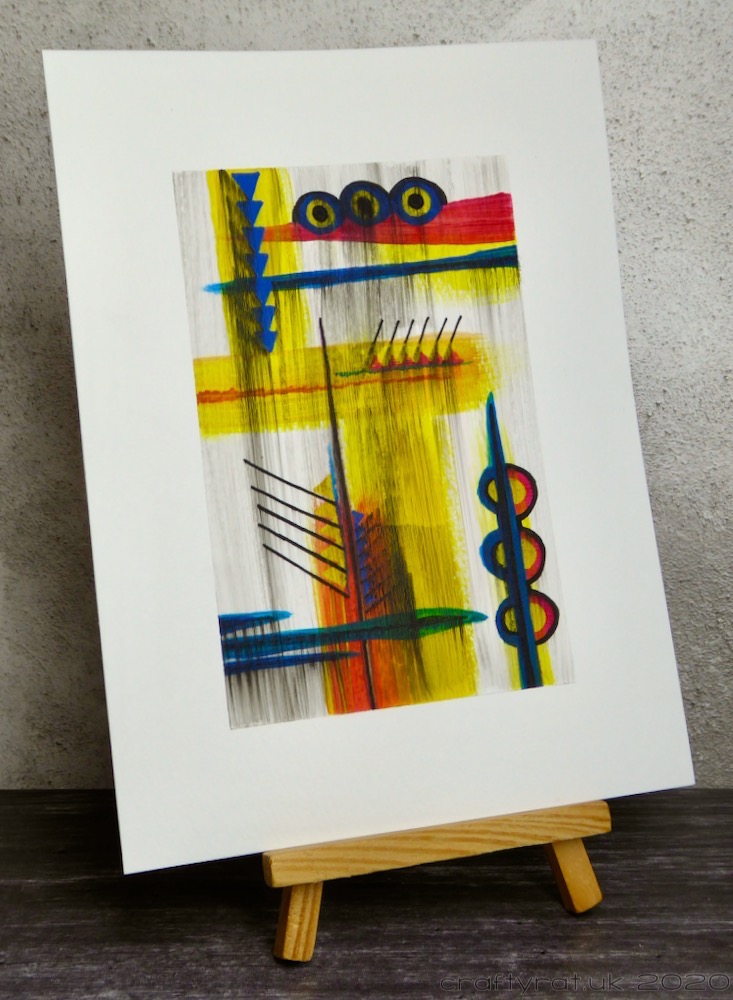 The abstract painting displayed on a mini wooden easel.