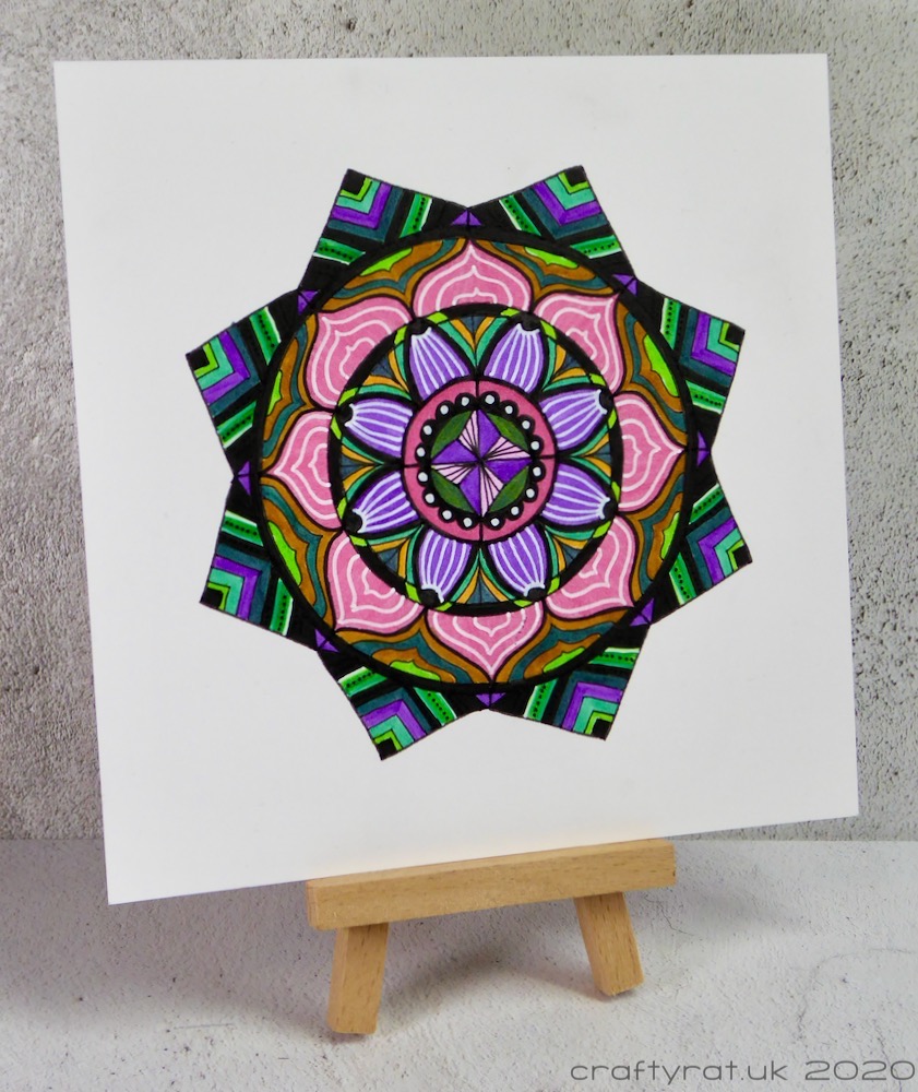 The mandala displayed on a small wooden easel.