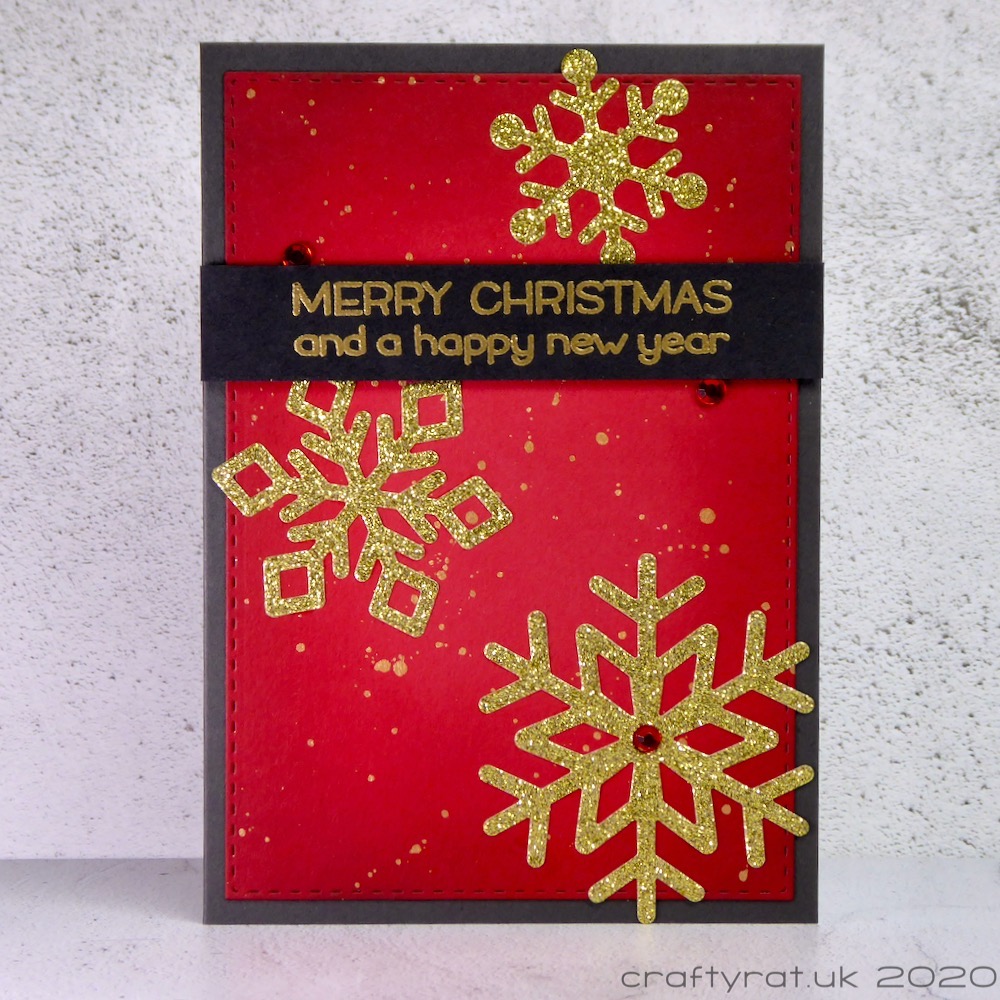 Christmas card with gold glitter snowflakes on a red background with gold splatters.