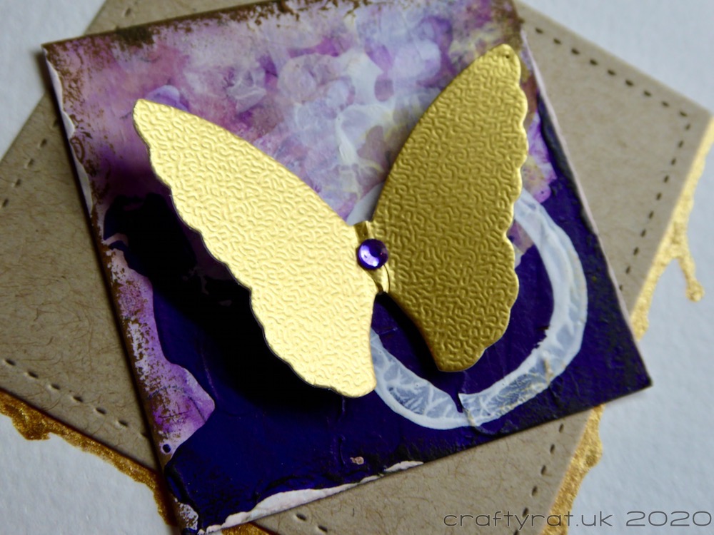 A close-up of the gold butterfly on the purple square.