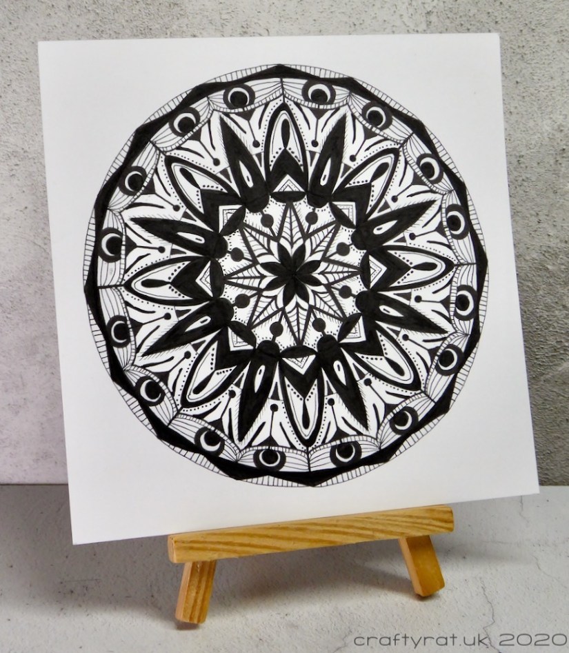 The black and white mandala displayed on a small wooden easel.