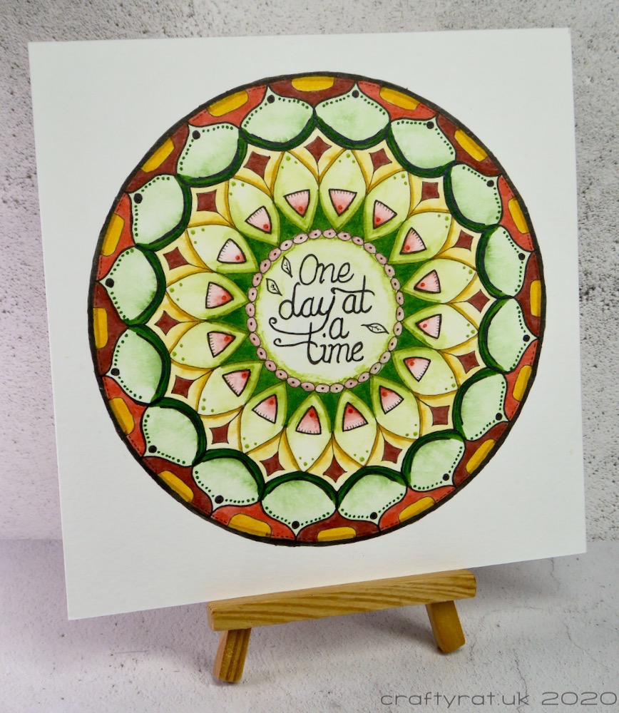 The mandala displayed on a small wooden easel.