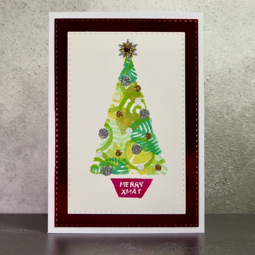 A card with a simple triangular Christmas tree stamped in a variety of patterns and topped with glitter dot ornaments.