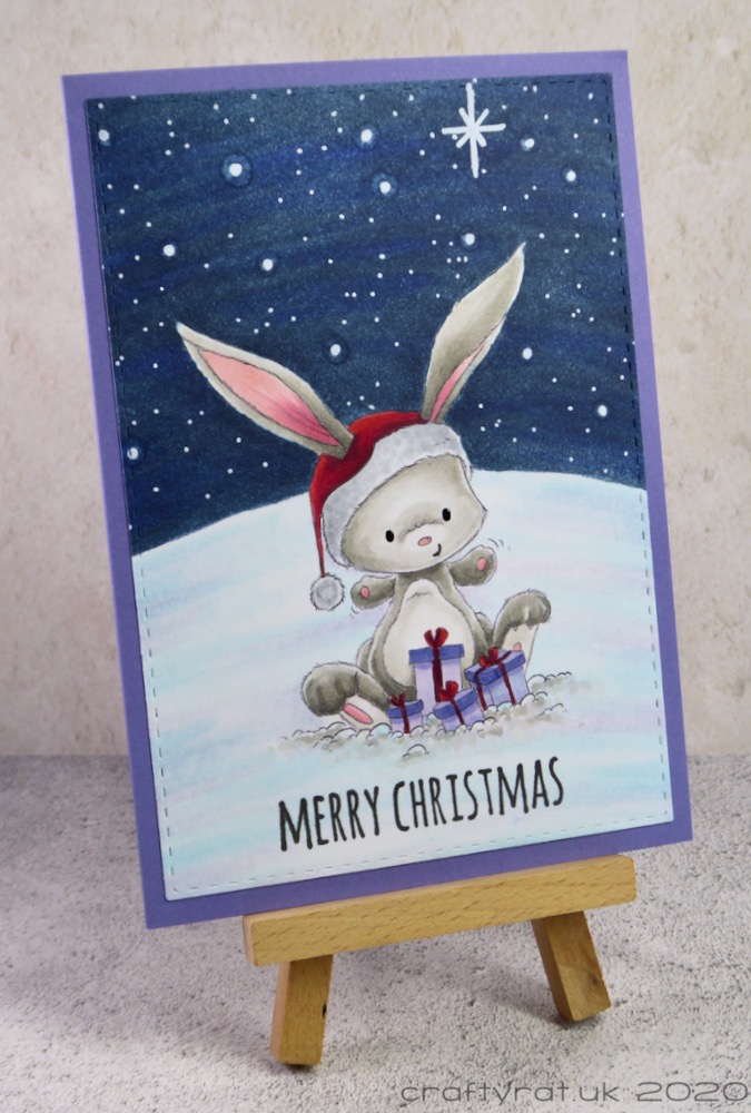 The Christmas card displayed on a small wooden easel.