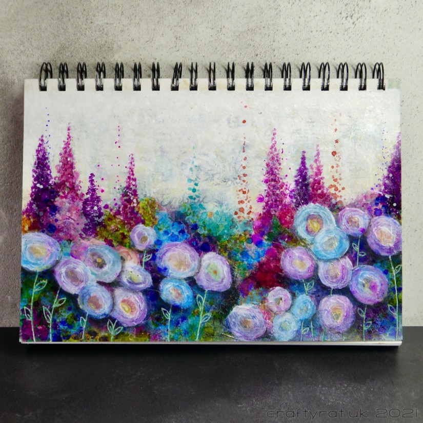 Art journal page with colourful flowers. Round flowers in the foreground and spiky ones at the back.