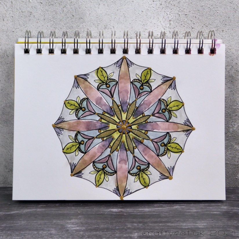 A hand-drawn mandala, loosely painted with muted purple, pink, blue and green.