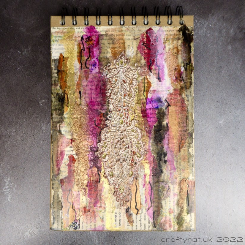 Sketchbook cover decorated with collage, paint drips and lace.